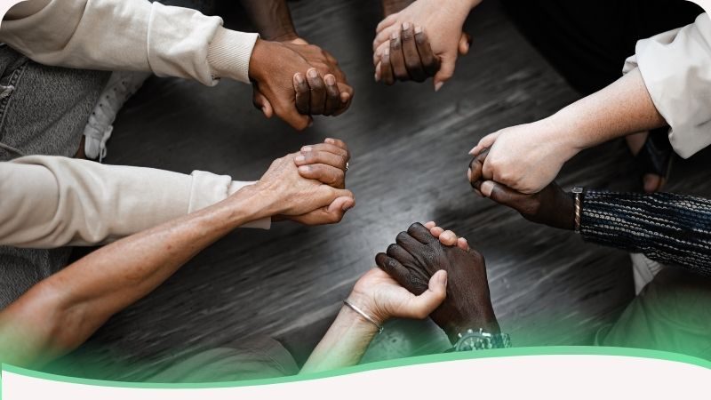 Mãos dadas de diferentes tons de pele representando o apoio mútuo e a rede de suporte emocional da psicologia