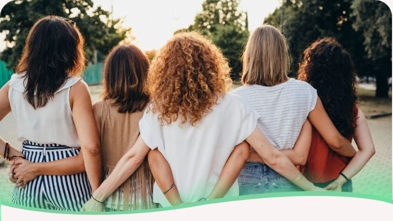 Mulheres de diferentes etnias abraçadas de costas simbolizando a união humana e o apoio emocional diante da vida